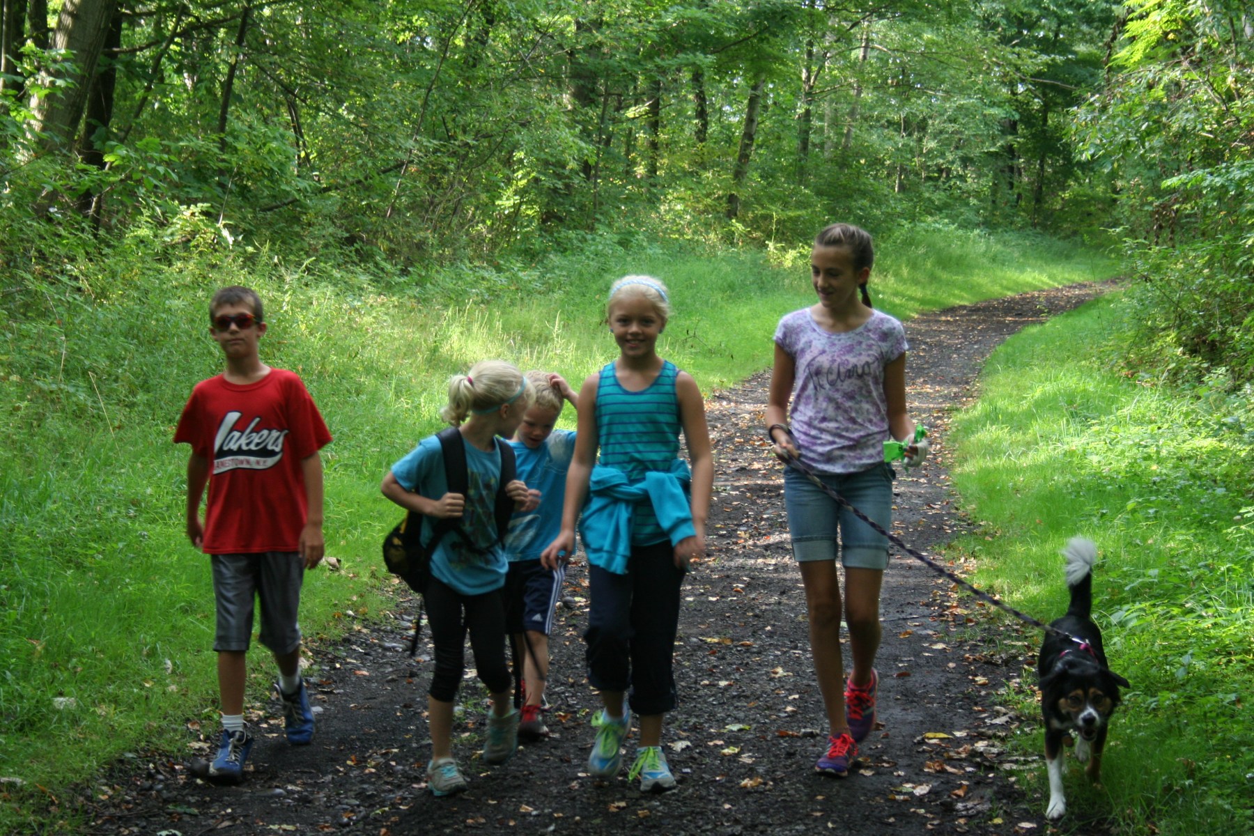 Happy children hiking with a dog.